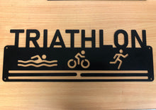 Load image into Gallery viewer, Triathlon medal display. swimmer, cyclist and runner with TRIATHLON text at top. 2 bars. matt black