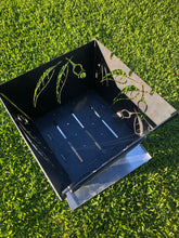 Load image into Gallery viewer, Ready to stack your firewood. There are also slots to place BBQ skewers or toast marshmallows. The cut out designs throw shadows from the fire to create a magical ambience..